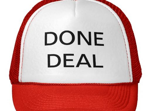 A red and white trucker hat with the words DONE DEAL printed in bold black letters on the front panel.