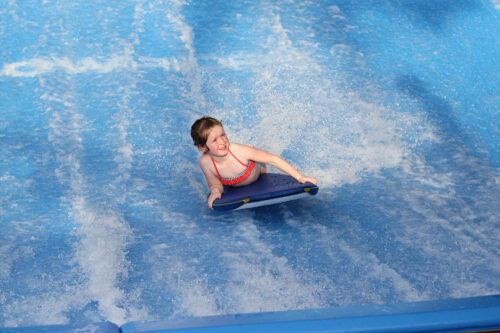 Little girl bodyboarding on a FlowRider wave machine