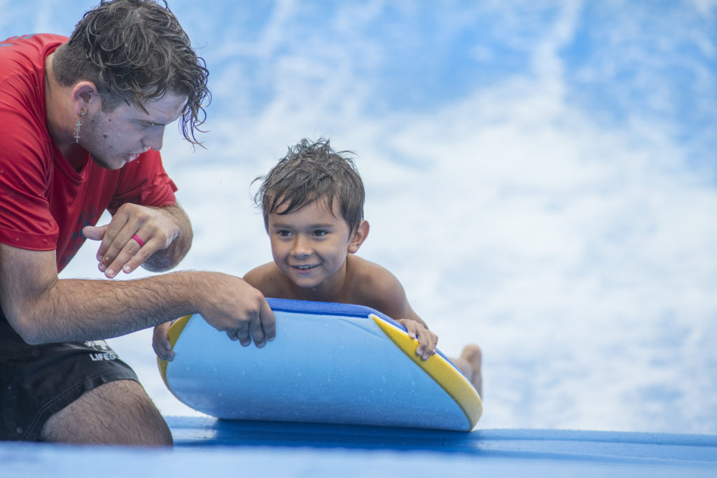 Smiling bodyboarder kid on FlowRider Surf Simulater at Soaky Mountain Waterpark