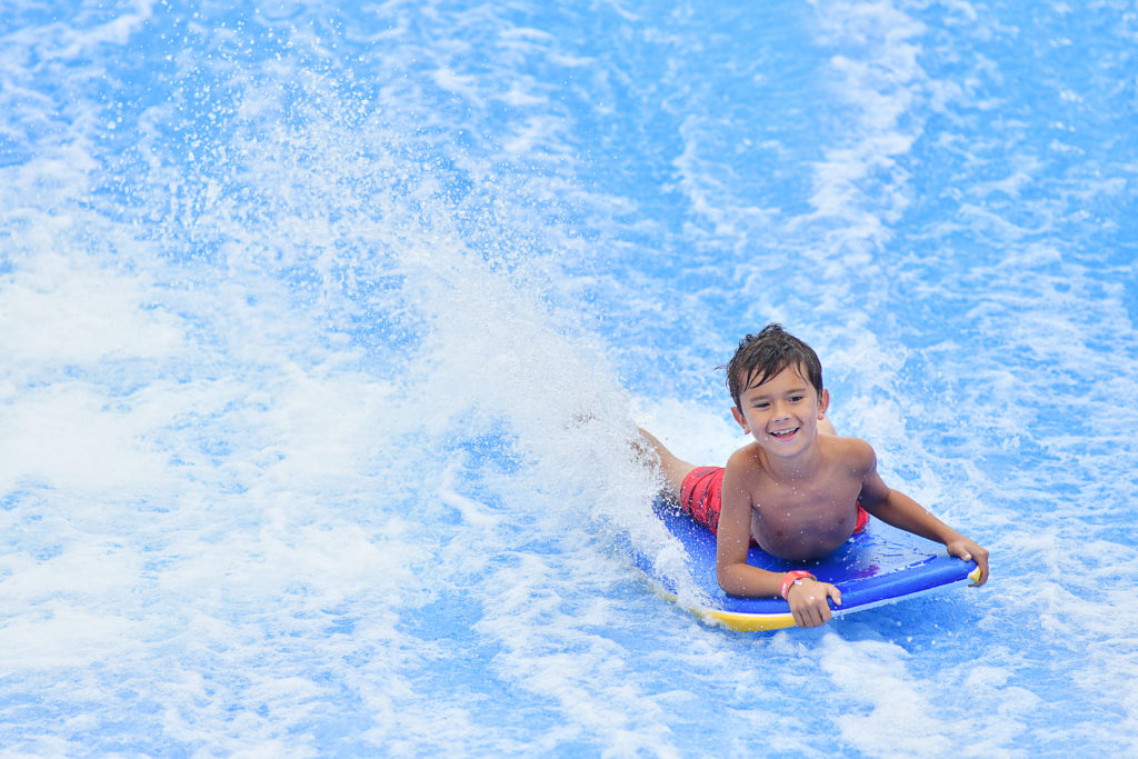 Happy boadyboarder riding FlowRider Surf Simulator at Soaky Mountain