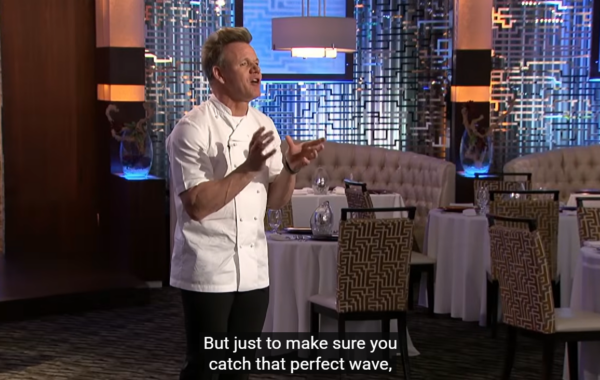 A chef in a white coat stands in a modern restaurant, gesturing with both hands. The subtitle reads, But just to make sure you catch that perfect FlowSurf wave, and tables are set in the background.